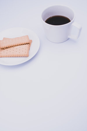 black coffee in a mug and plate with biscuits on a white background with copy spaceの写真素材