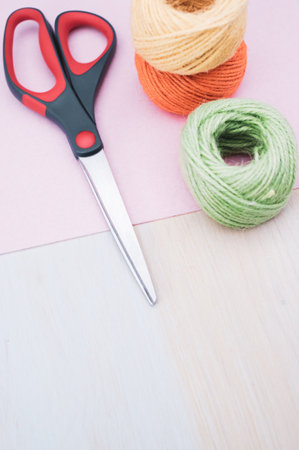 multicolor decoration yarns with scissors on a bright wooden background with copy space