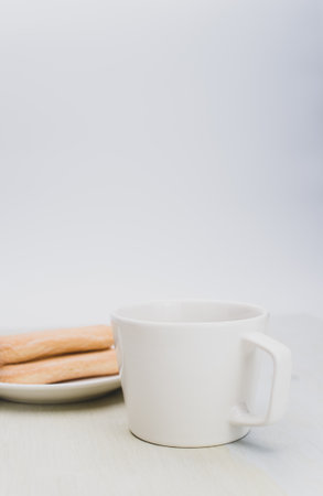 black coffee in a mug and plate with savoiardi biscuits on a white background with copy spaceの写真素材