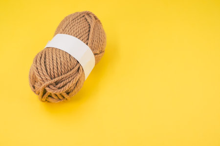 A vertical shot of isolated beige yarn on yellow background with text spaceの写真素材