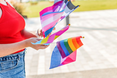 Female hands holding lgbtq, bisexual, asexual, transgender, lesbian and pan sexual flag. Selective focus.の写真素材