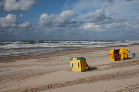 beach chairs and playground equipment on an empty beach in the sunshineの写真素材