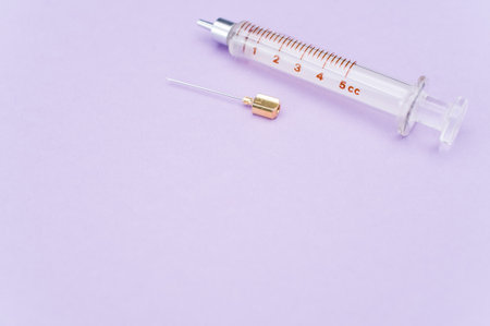 an isolated injection syringe on mauve paper background with text spaceの写真素材