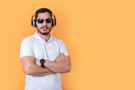 Young man with beard and sunglasses, listening to music with wireless headphones. Look at camera.の写真素材
