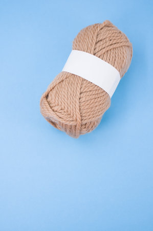 A vertical shot of isolated beige yarn on blue background with text space