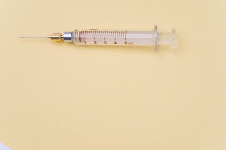 an isolated injection syringe on yellow paper background with text spaceの写真素材