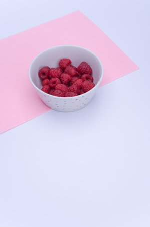 sweet tasty raspberries in a bowl on multicolored background and copy spaceの写真素材
