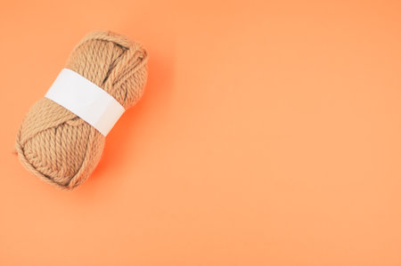 A vertical shot of isolated beige yarn on orange background with text spaceの写真素材