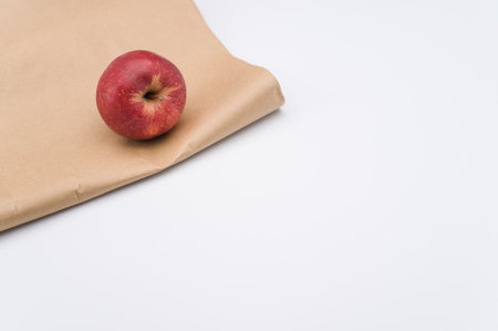 ripe biologic red apple on a white and  background and paper bag with copy spaceの写真素材