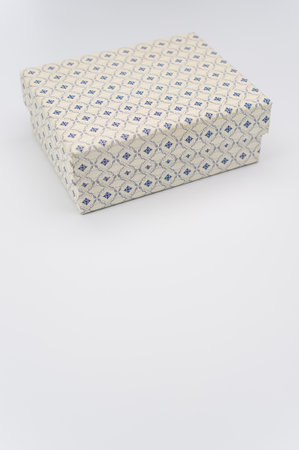 a closed white paperboard decorated box on white background with text spaceの写真素材