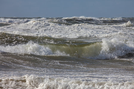 Waves of the north sea with white spindrift in front of a blue skyの写真素材