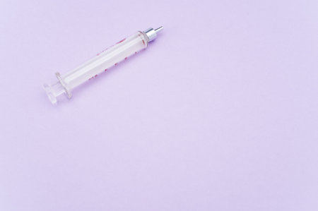 an isolated injection syringe on mauve paper background with text spaceの写真素材