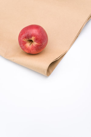 ripe biologic red apple on a white and  background and paper bag with copy spaceの写真素材