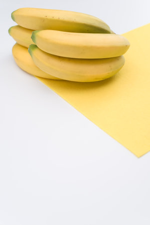 ripe biologic bananas on a white and yellow background with copy spaceの写真素材