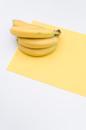 ripe biologic bananas on a white and yellow background with copy spaceの写真素材