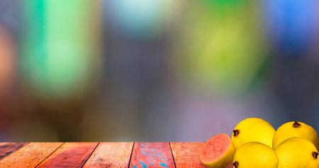Wooden table with guavas and blurred colored background.