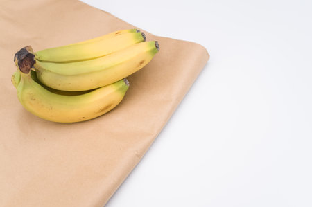 ripe biologic bananas on a white and  background and paper bag with copy spaceの写真素材