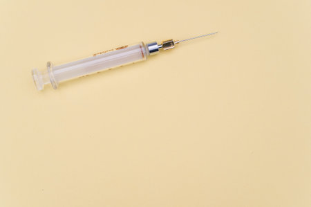an isolated injection syringe on yellow paper background with text spaceの写真素材