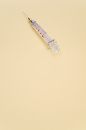 an isolated injection syringe on yellow paper background with text spaceの写真素材