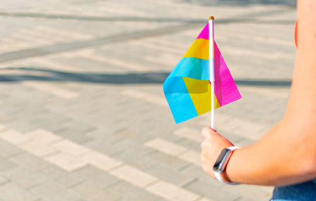 Female hand holding small lgbt pan sexual flag. LGBT pride flag.の写真素材