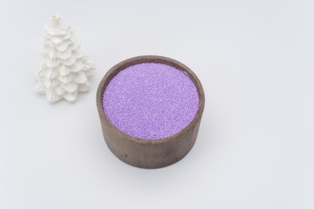 Christmas ornamental background with fir tree and vase with magenta sand on a white surface with copy spaceの写真素材