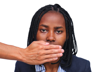 Unrecognizable person covering mouth of a serious african american woman against a white background.