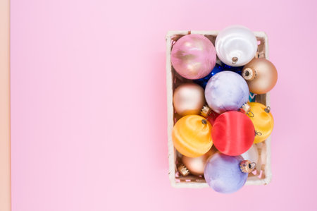 Multicolored Christmas decorative balls in a wicker canister with sapce for text on pink surfaceの写真素材