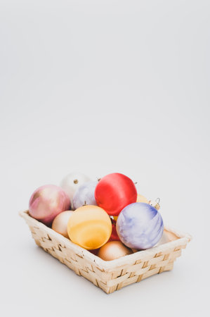 Multicolored Christmas decorative balls in a wicker canister with sapce for textの写真素材