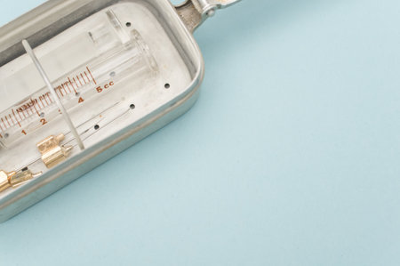 an isolated injection syringe and needles in a box  on blue paper background with text space