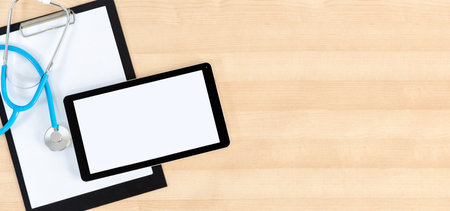Clipboard, tablet and stethoscope on wooden desk. Online doctor concept.