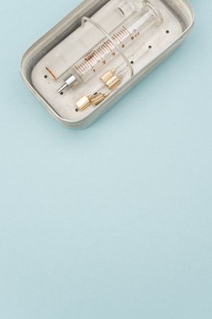 an isolated injection syringe and needles in a box  on blue paper background with text space