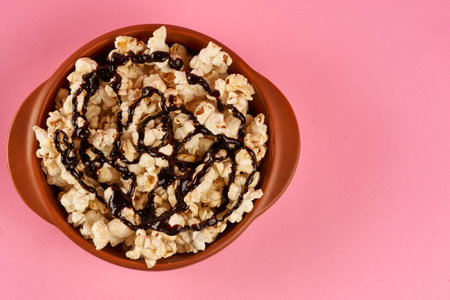 top view bowl with sweet popcorn with chocolate sauce on a pink background