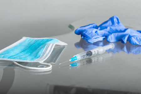syringe, blue hygienic protective mask and blue rubber gloves, on the glass table, ready to be used...