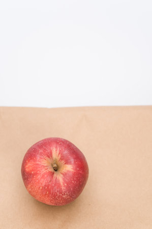 ripe biologic red apple on a white and  background and paper bag with copy spaceの写真素材