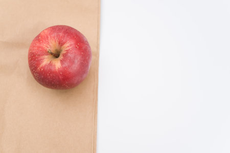 ripe biologic red apple on a white and  background and paper bag with copy spaceの写真素材