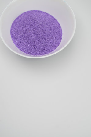 lilac sand in a white ceramic bowl on a white background with copy space