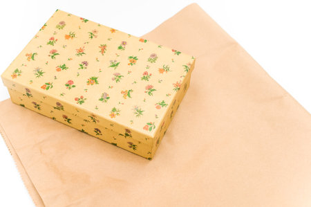a closed paperboard decorated box on white and kraft paper background with text space