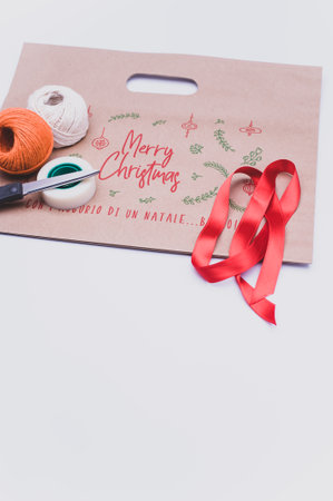Merry Christmas decorated paper bag with decorative yarn ribbon and scissors with copy spaceの写真素材
