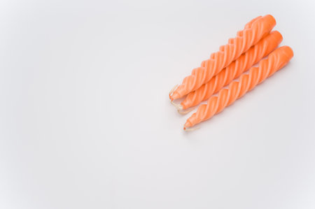 bunch of orange candles on a white surface with space for textの写真素材