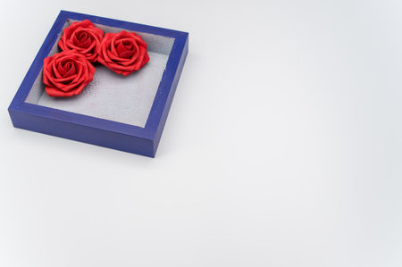 a blue wooden box with three red roses on a white background with text space