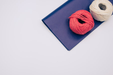 decorative yarn balls with blue paper sheet scissors and tape on a white surface