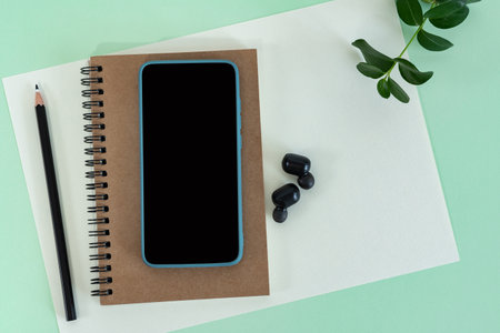 Flat lay desk workspace with empty blank paper, notebook and mobile phone.の写真素材