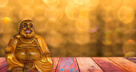Wooden smiling buddha and gold background with bokeh.の写真素材