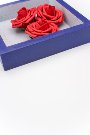 a blue wooden box with three red roses on a white background with text space
