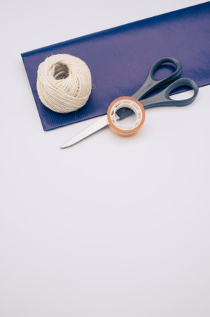 decorative yarn balls with blue paper sheet scissors and tape on a white surfaceの写真素材