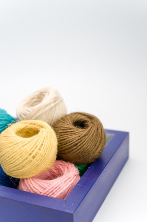 multicolored decorative yarn balls in a wooden box on a white surfaceの写真素材