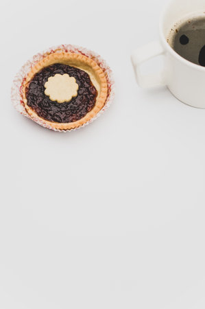 isolated cherry jam tart in a paper backing cup and coffee on a white background with text spaceの写真素材
