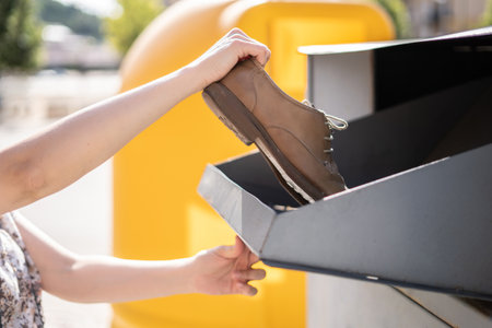 Hands putting used shoes into clothing container, recycling, second chance.の写真素材