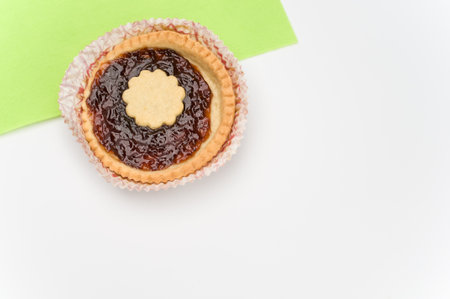 isolated cherry jam tart in a paper backing cup on a white green background with text spaceの写真素材