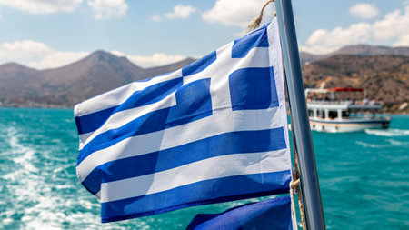 A waving flag of Greece on a ship off the Greek coastの写真素材